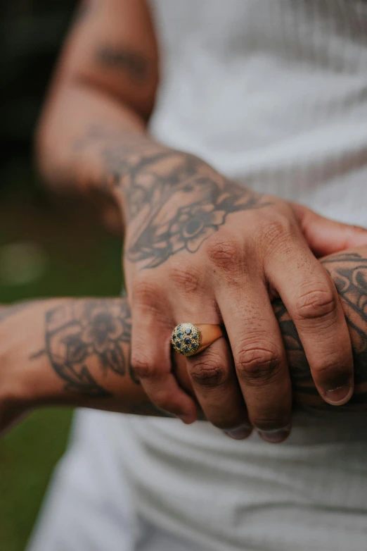 a close - up of a tattooed man holding a ring