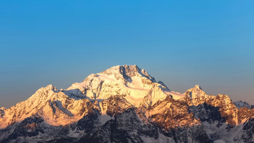 snowy mountain peaks against a blue sky with a moon