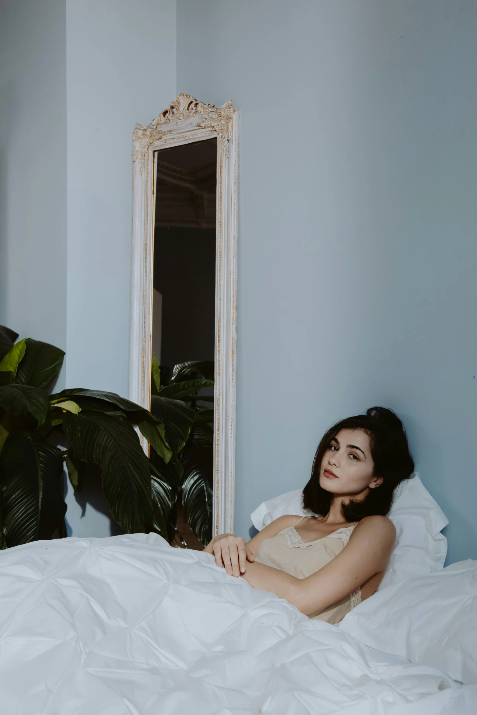 a woman sitting in bed with her arm resting on the pillow