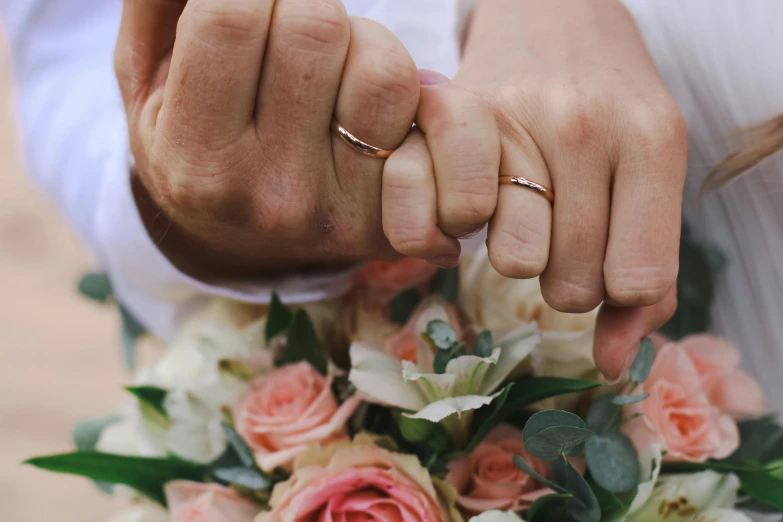 a couple holding hands over the top of their wedding bouquet