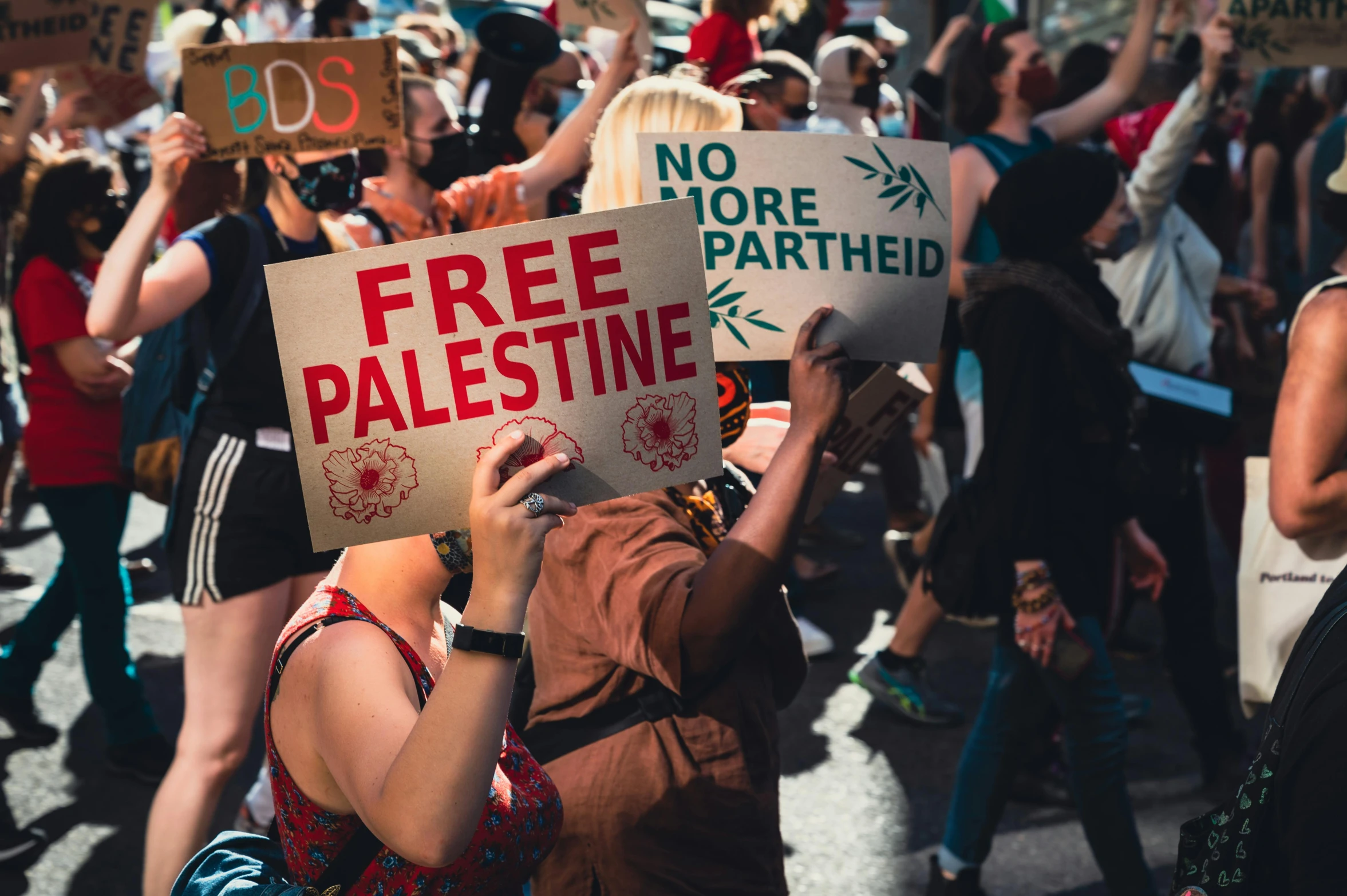 people are outside holding up signs that read free palestine