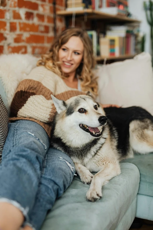 a woman is sitting on a couch with a large dog