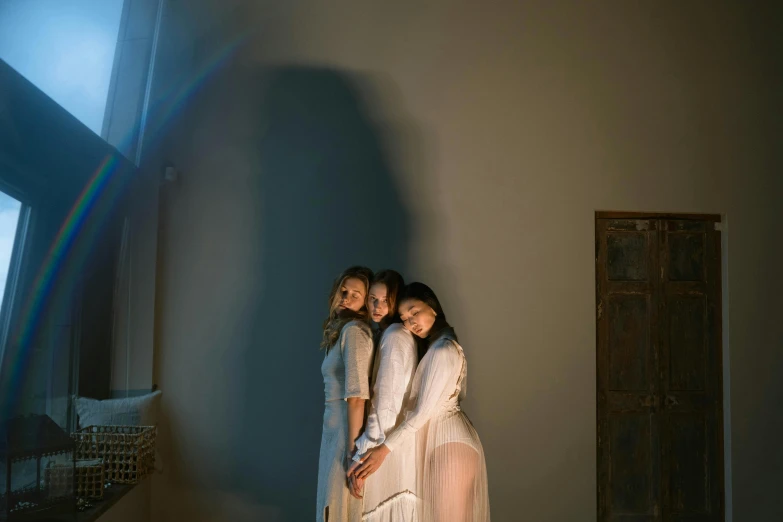 four girls in dresses with the rainbow light shining behind them