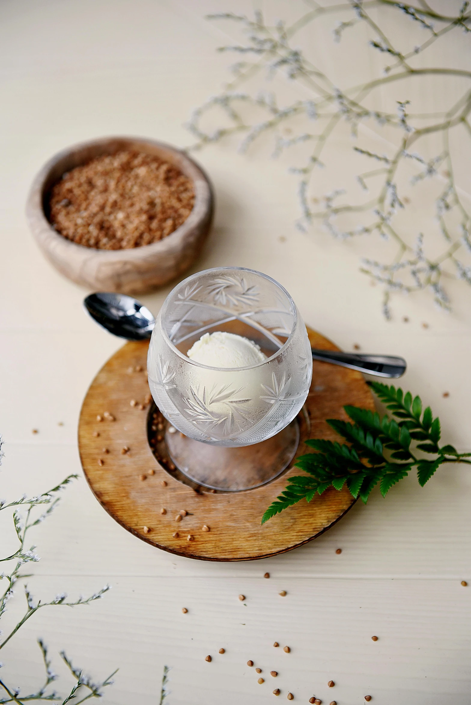 a table with a wooden coaster holding a glass and a spoon