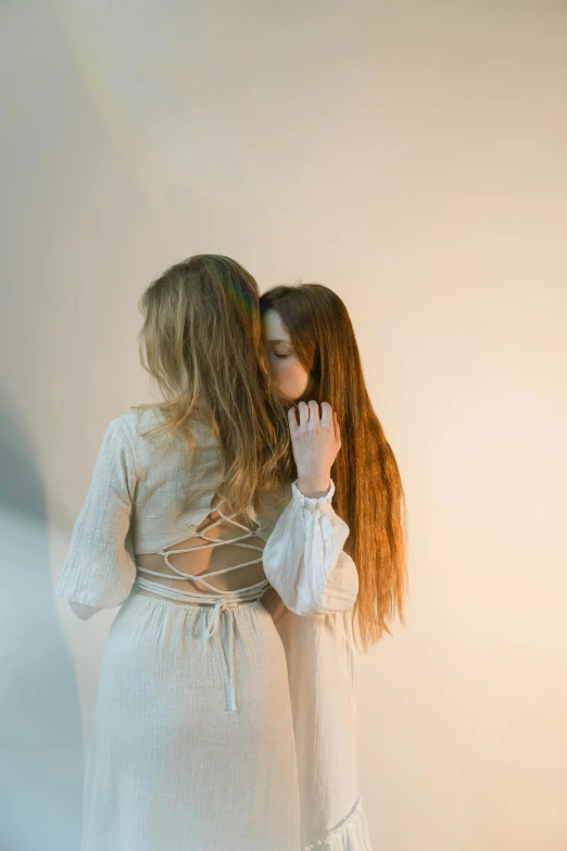 two girls are hugging in the back with their hands touching their faces