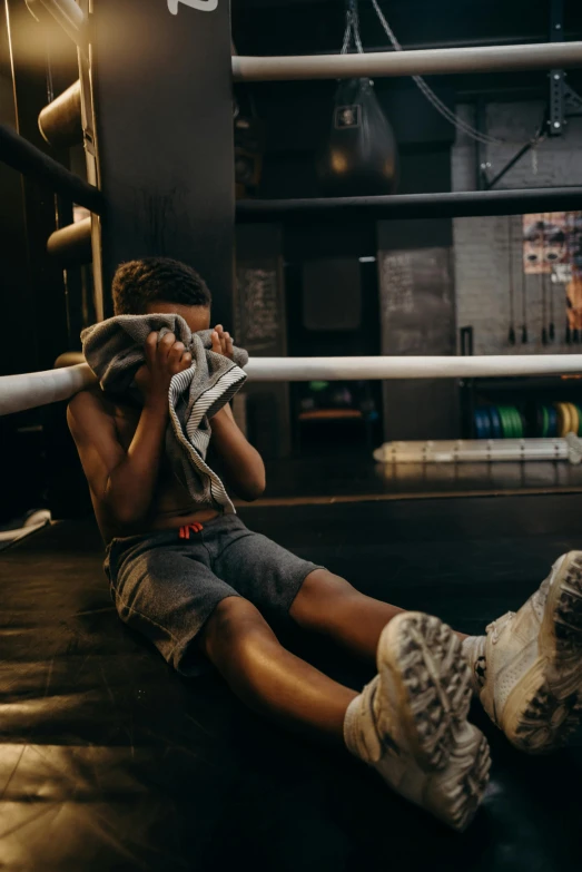 a little boy sitting on a wrestling ring