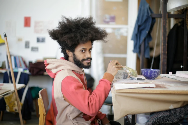 a man with long hair is working on his piece of artwork