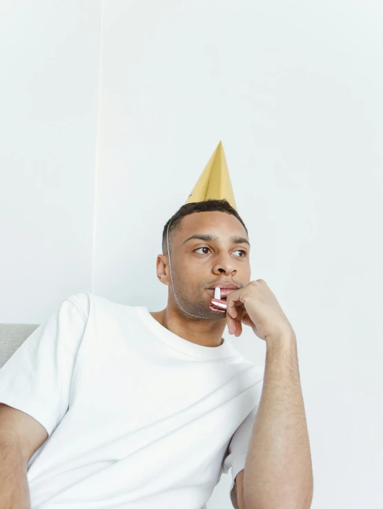 a man in a party hat and one finger on his mouth