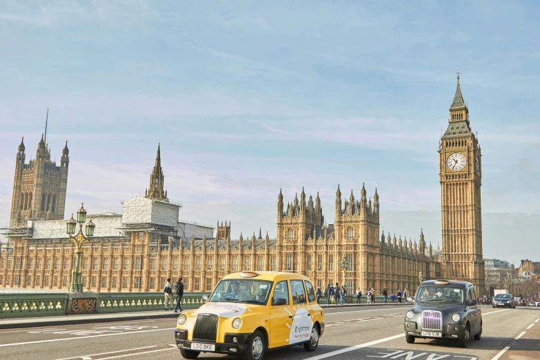 two taxis driving in front of a clock tower and some big buildings