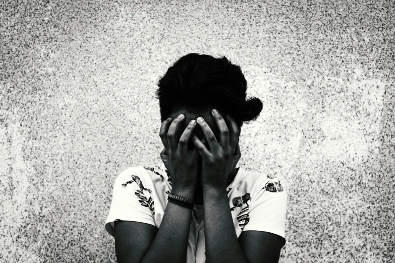 a woman covering her face against a wall