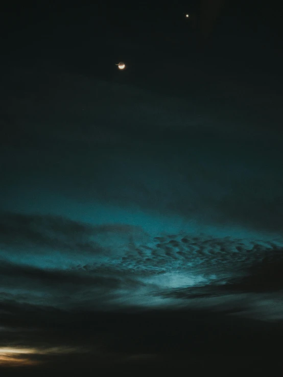 a blue and white night sky with two planets in the distance