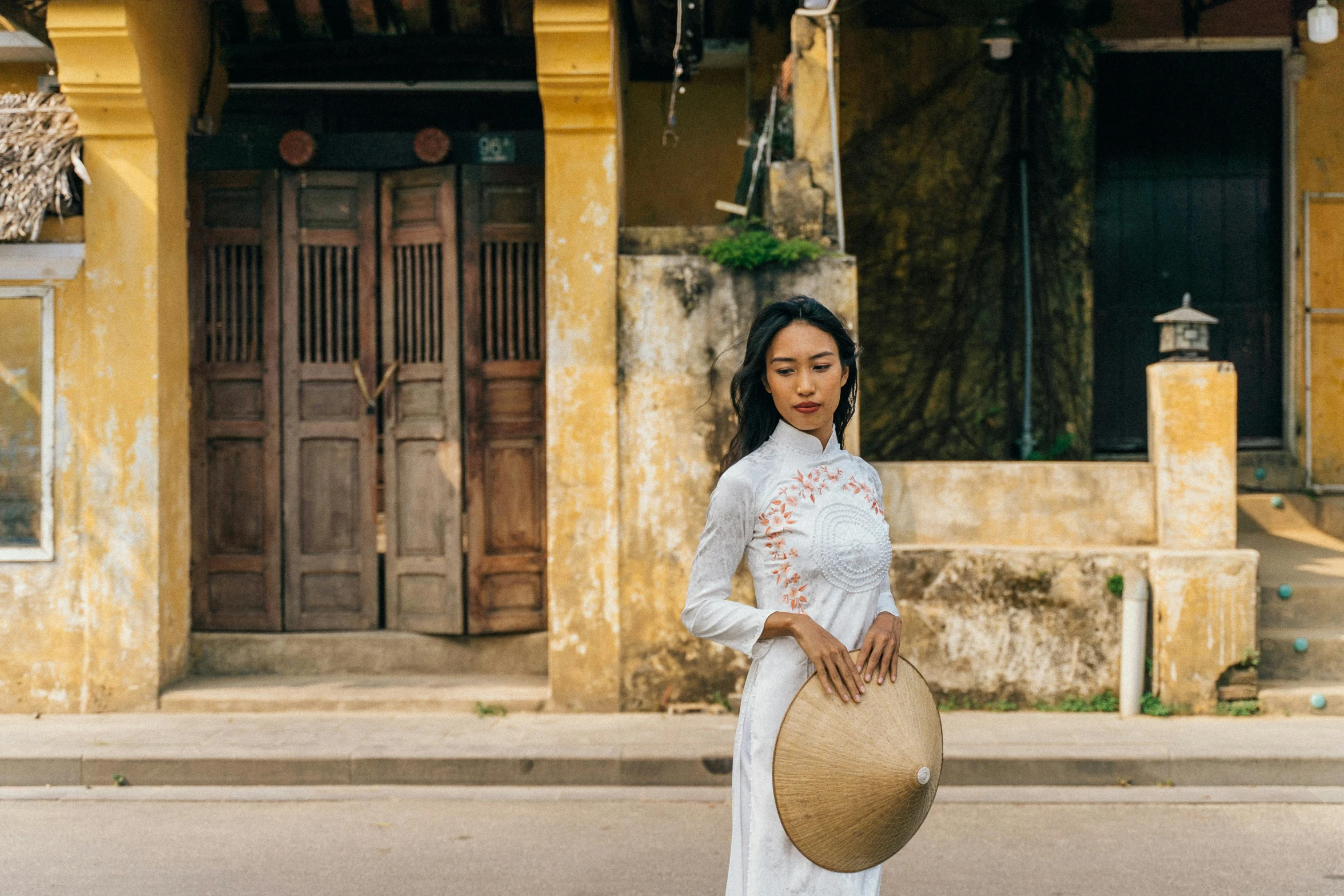 a woman wearing white poses with a big brown hat