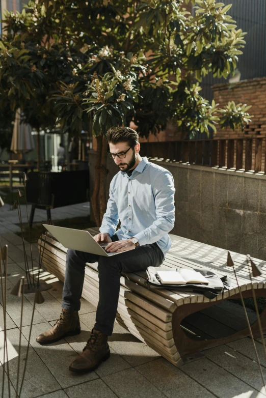 a man sitting on top of a wooden bench while writing