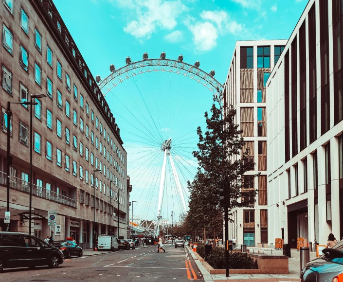 a large ferris wheel sitting behind tall buildings