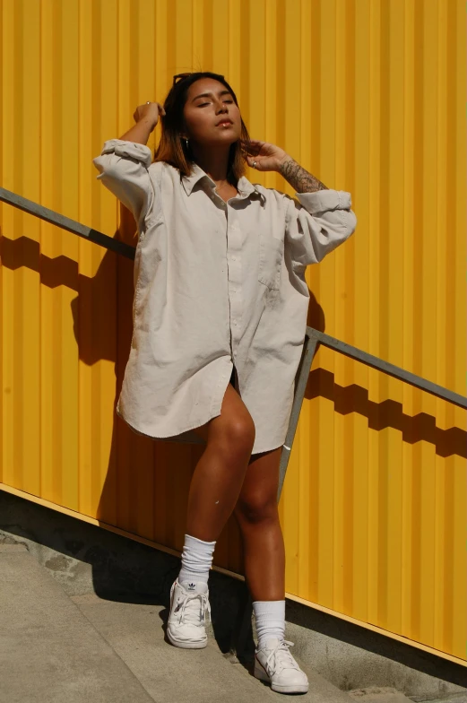 a young woman leaning against a yellow wall while wearing high heels