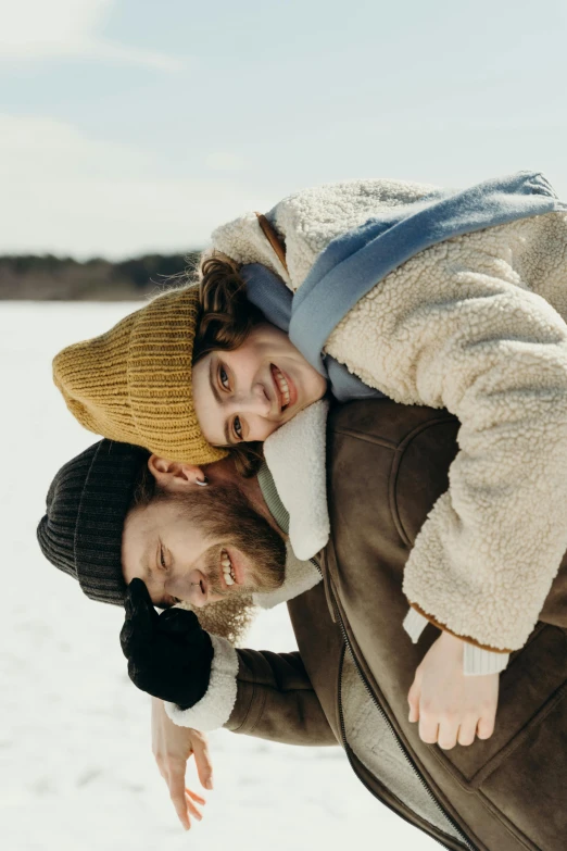 two people with hats posing for a pograph in the snow