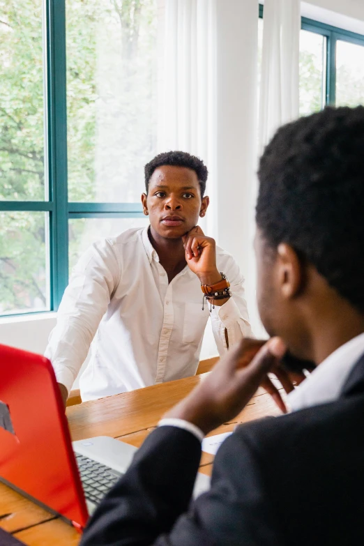 two men are talking at a meeting in front of the computer