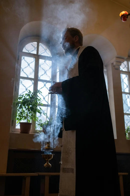 a priest looking at smoke coming out of his mantle