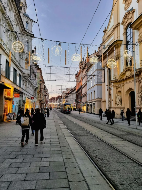 the street has people walking down the sidewalks in front of some buildings