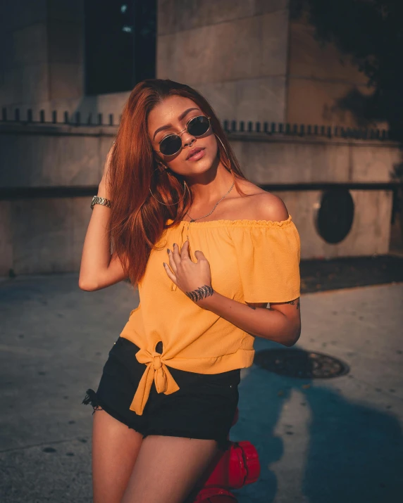 woman wearing sunglasses poses outdoors with arms folded