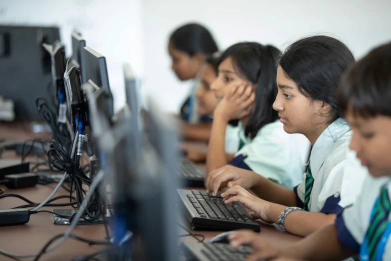 several children are using computer keyboards in a classroom
