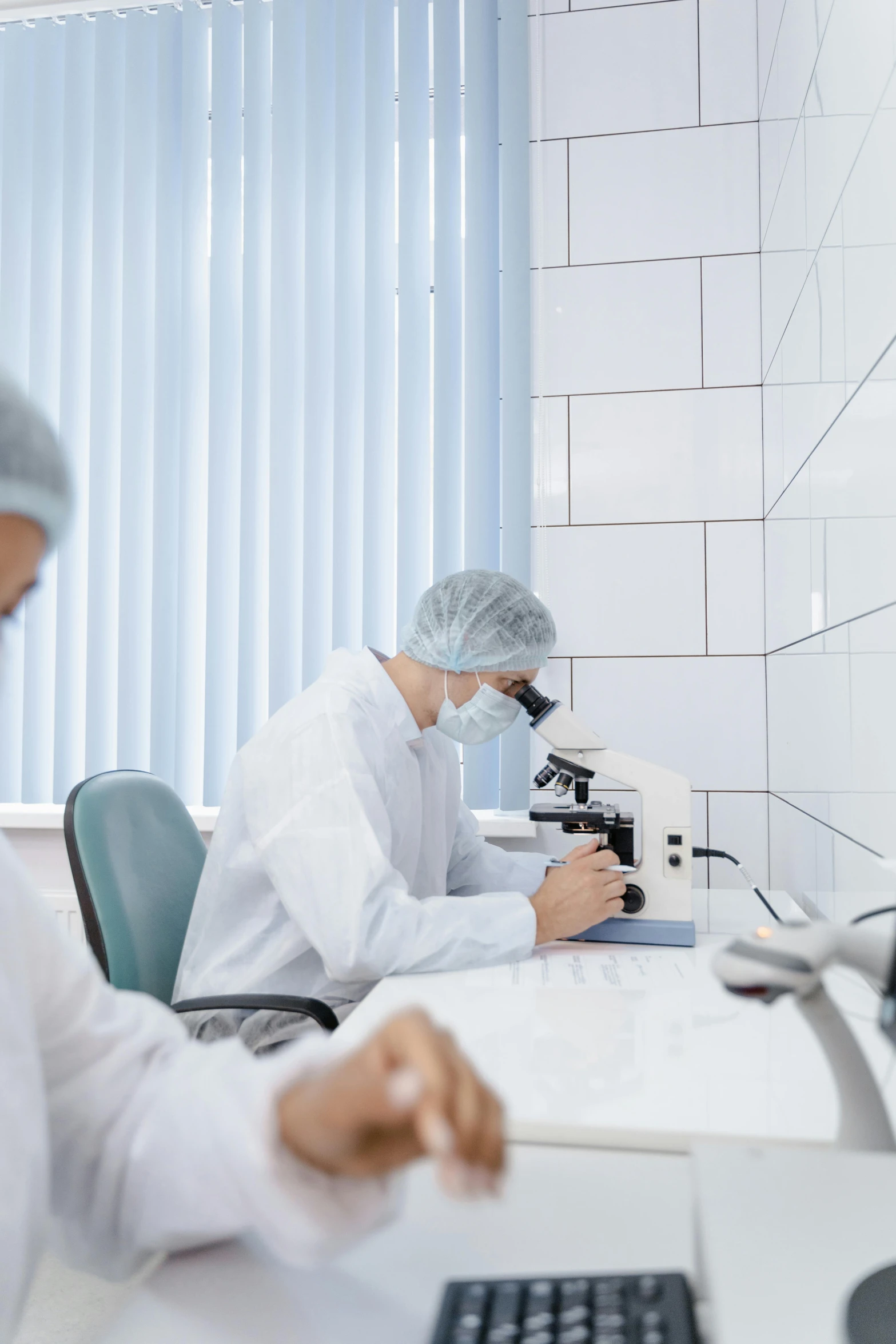 two people are doing research in front of a microscope