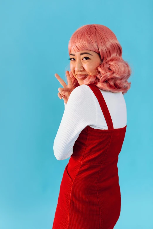 a woman with pink hair making the okay hand sign