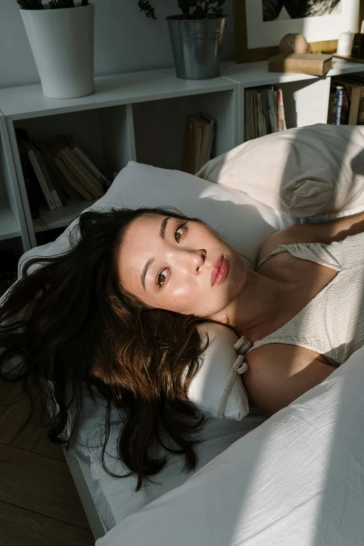 a woman lying on a white sheet on top of a bed