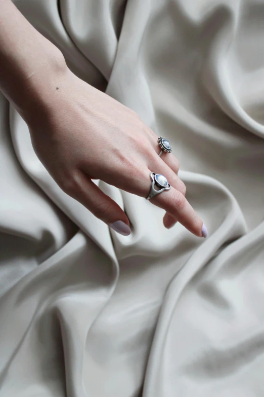 a person with nail polish and ring setting on a sheet