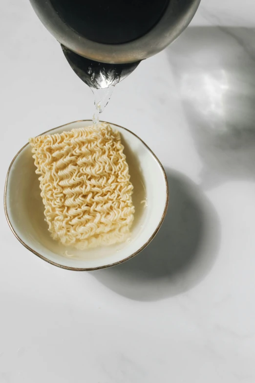 noodles in a white dish being washed under a black liquid