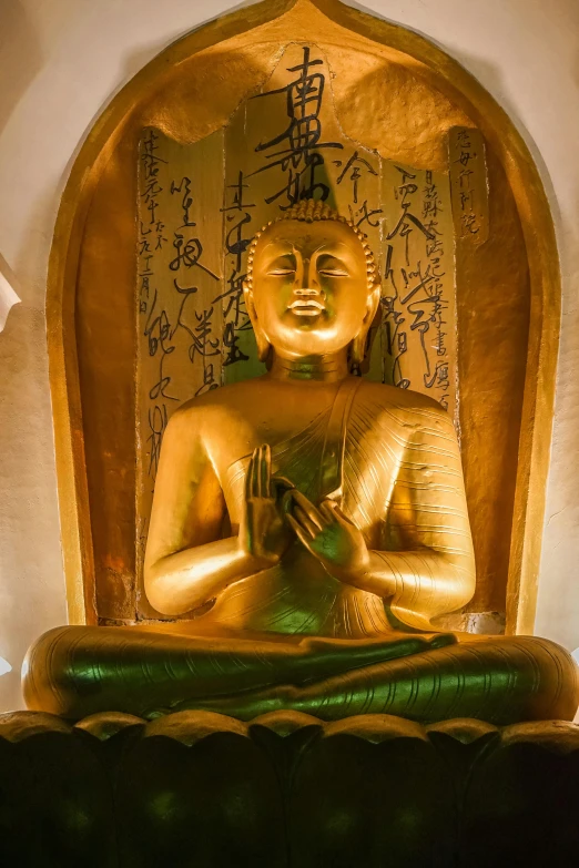 buddha statue sitting on its feet in front of a gold framed piece