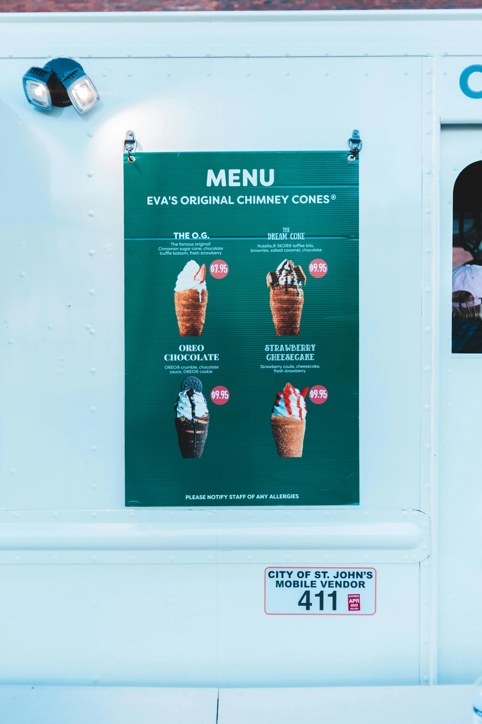 a menu board on a building with people sitting at a table