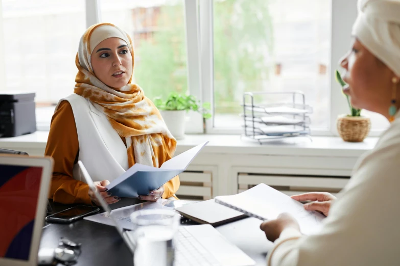 two women talking around a desk