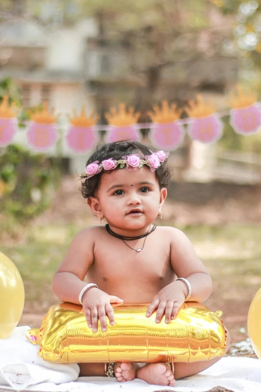 an indian baby in her bathing suit holding an inflatable balloon