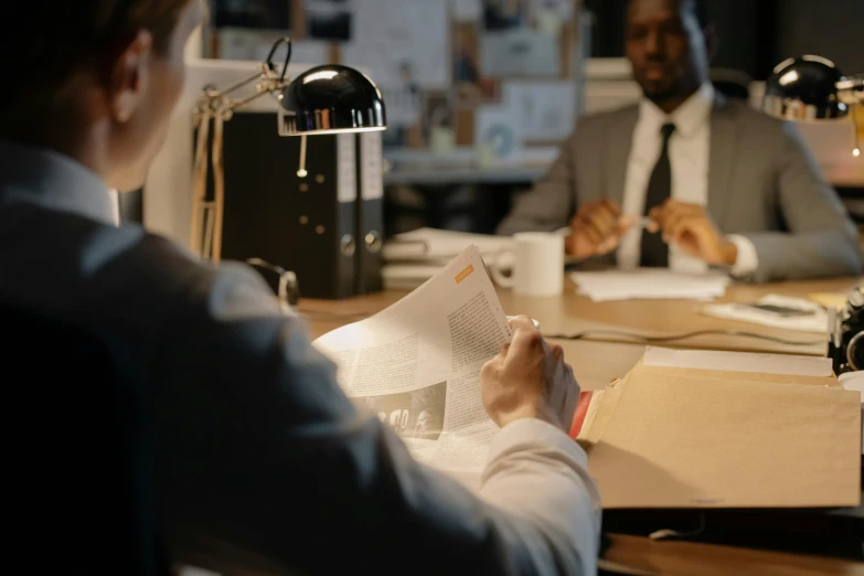 people sitting at desk in front of two monitors