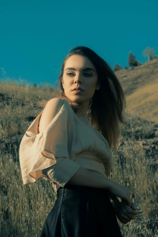 a young woman with dark hair posing in a field