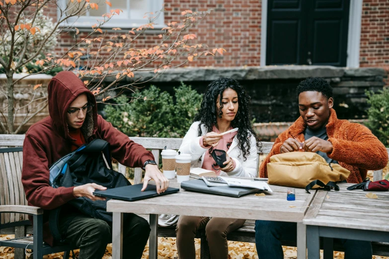 three women sit at an outdoor table outside