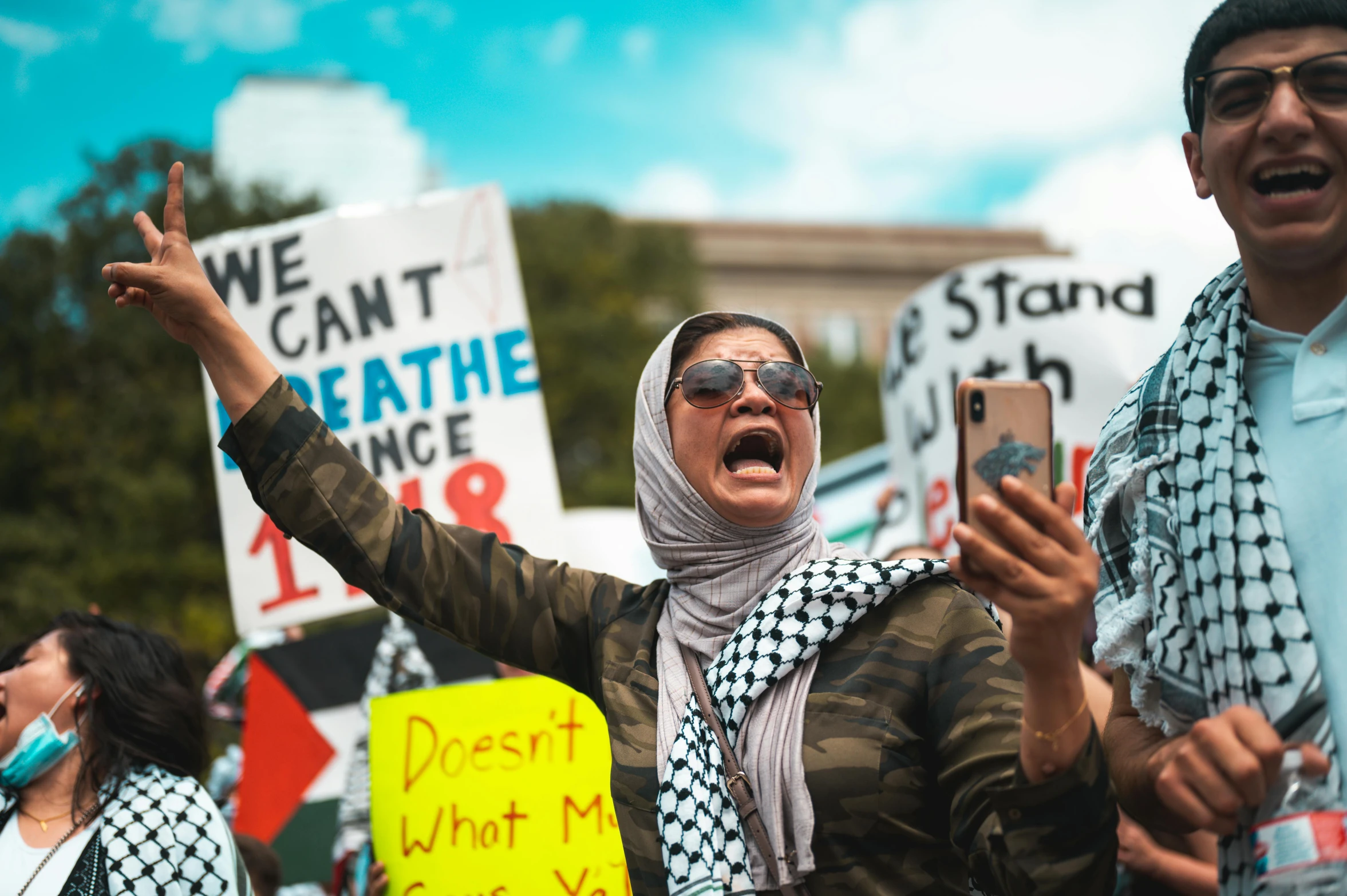 a woman yells with both hands while standing next to a protester