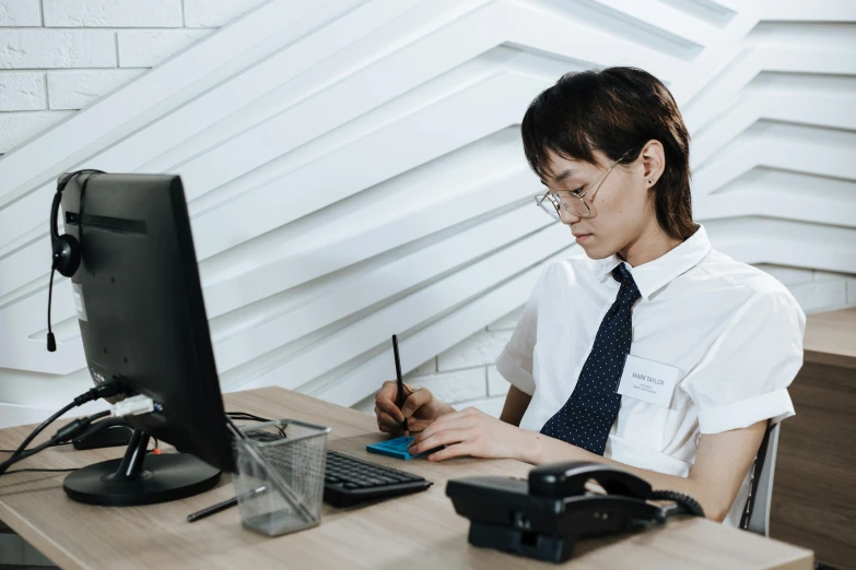 a person sitting at a desk with a pen and computer