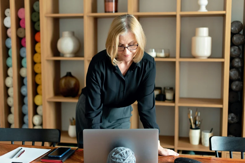 a woman sitting at a table next to a laptop computer