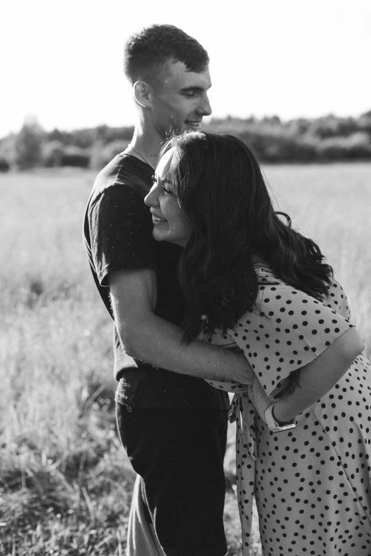 a couple is hugging in the middle of the field