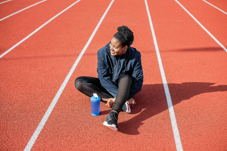 a man sitting on the side of a track next to a blue bottle