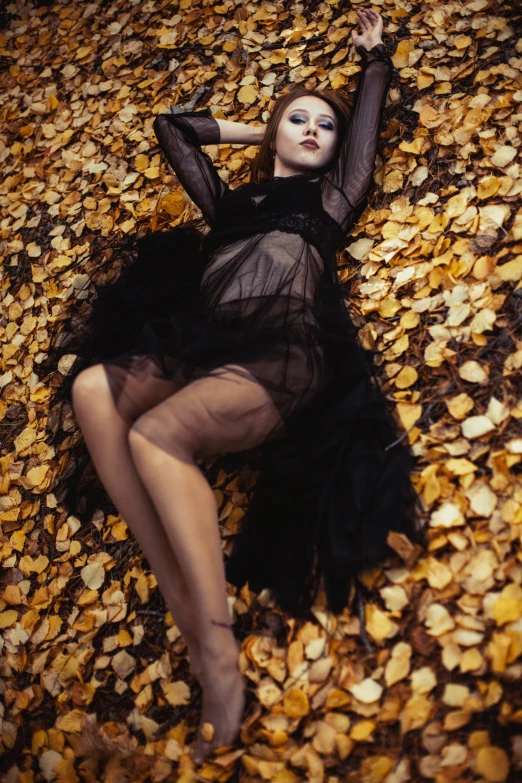 the woman has her arm up on a leaf covered area