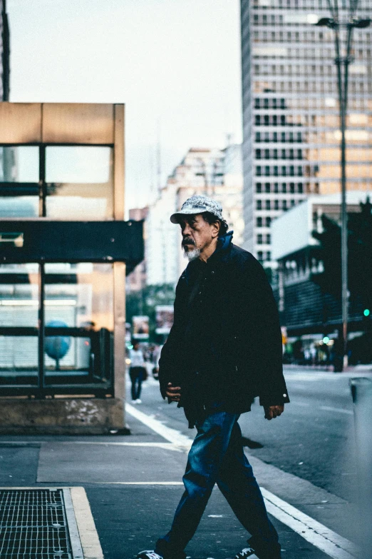 a man walking across a street in the evening