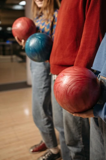 people holding bowling balls on top of a bowling court