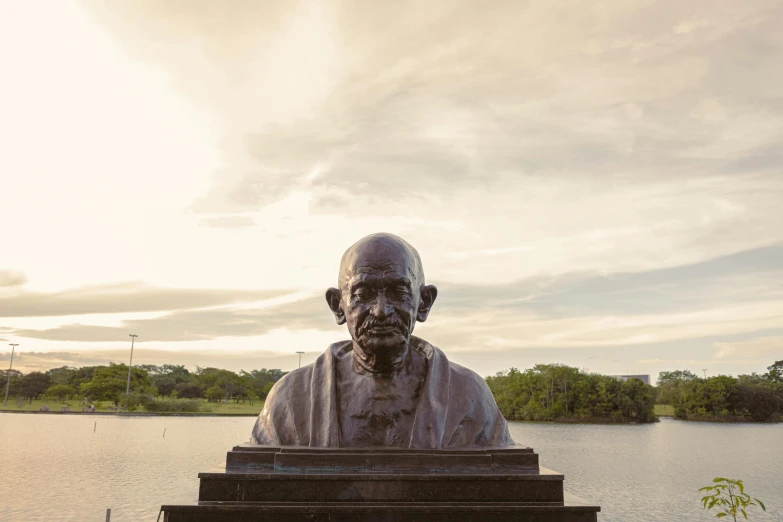 a large statue of a man sitting next to water