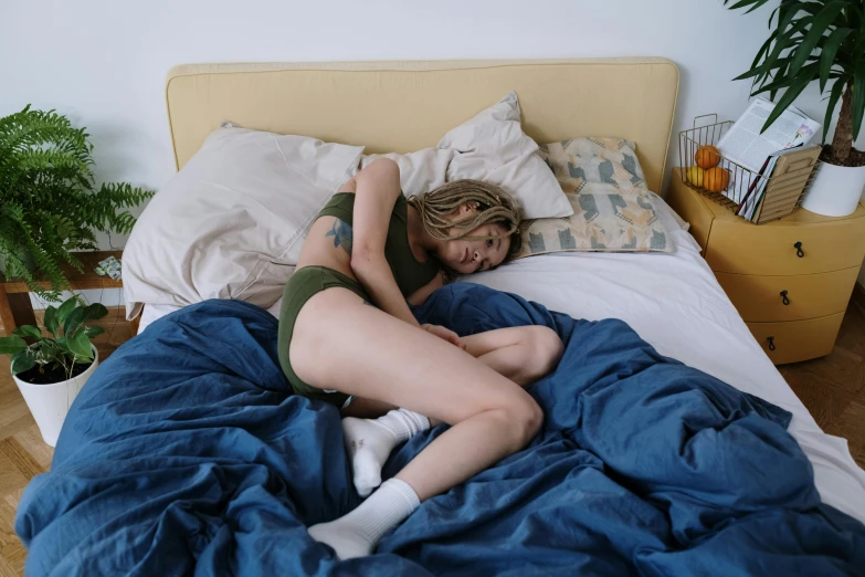 woman lying in bed with blue sheets and her arms folded