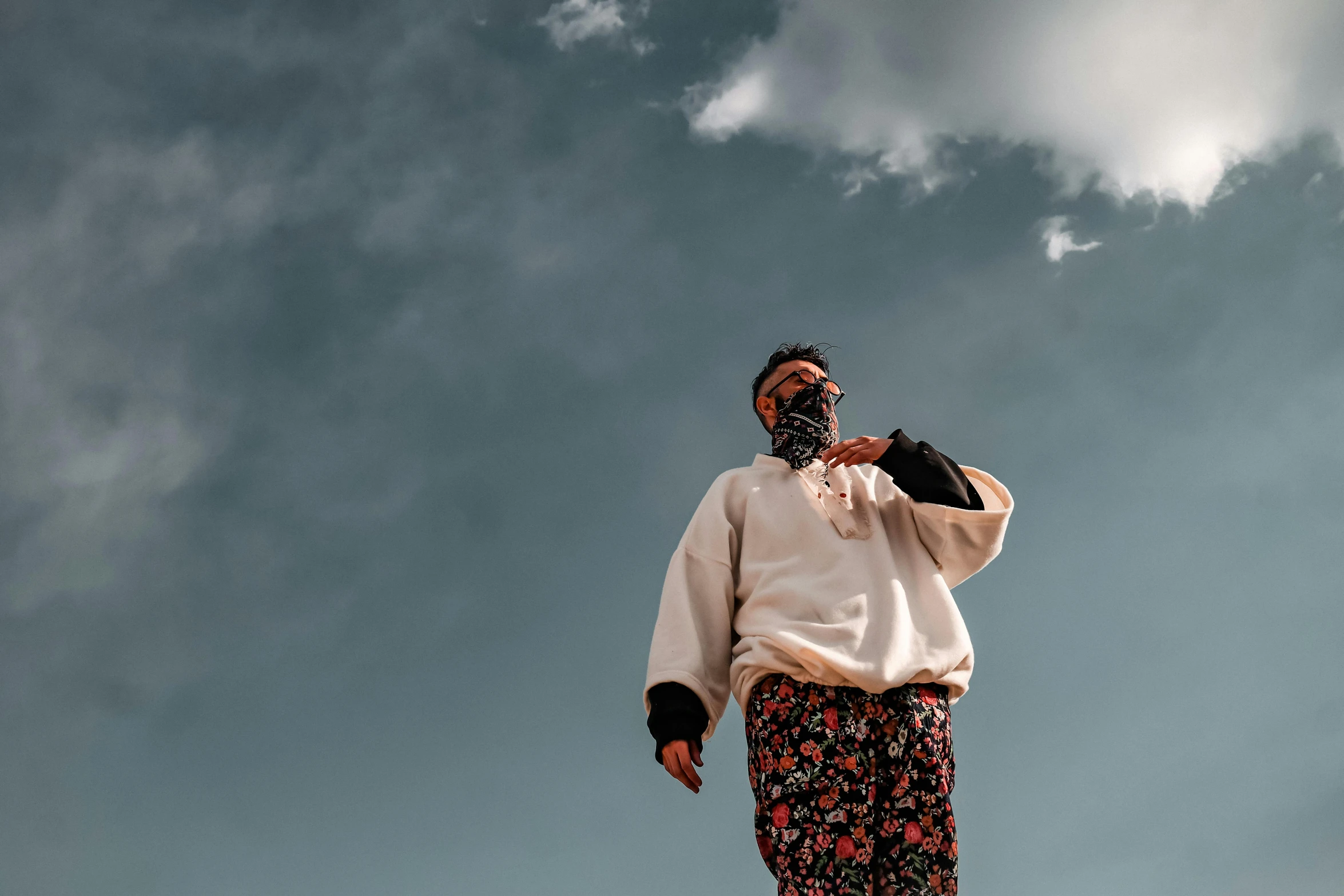 a man standing on a ledge in front of the clouds