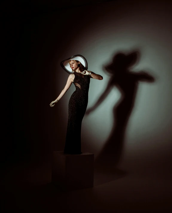 a woman in a dress and hat standing in front of a shadow on a wall