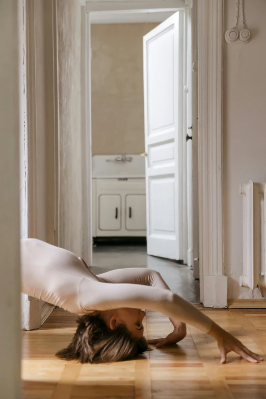 a woman practices yoga on a hard wood floor